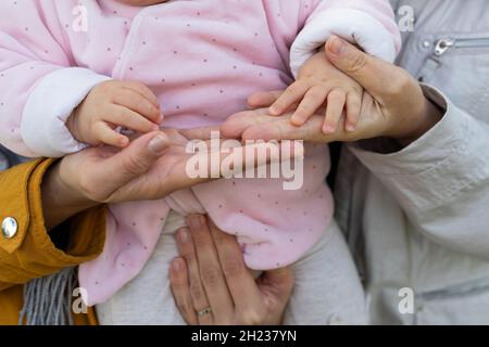 Nahaufnahme des Bildes von Mutter und Großmutter, die die Hände des Babys halten. Liebe pur Stockfoto