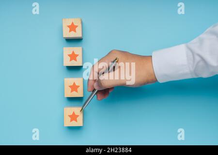 Die besten ausgezeichneten Business Services Bewertung Customer Experience Konzept von fünf Sternen auf Holzblock auf blauem Hintergrund Stockfoto