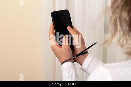 Frau, die das Smartphone mit den mit Handschellen gefesselten Händen hält. Suchtkonzept für Mobiltelefone. Stockfoto