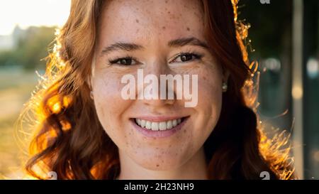 Junge Frau mit lockigen Kupferhaaren und Sommersprossen im Park Stockfoto