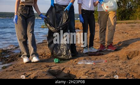 Nicht erkennbare Familie sammelt Plastikmüll in Beuteln in der Nähe der Küste Stockfoto