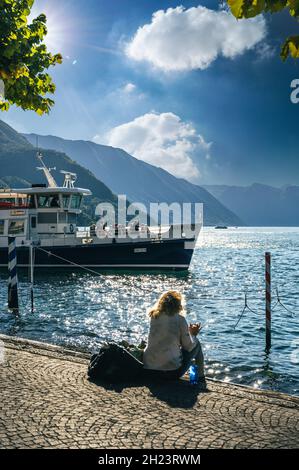 Tourist sitzt am See in der kleinen malerischen Stadt Bellagio im Comer See, Italien Stockfoto