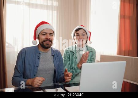 Glückliches junges Paar verwenden oder schauen etwas auf Laptop-pc für weihnachten. Videoanruf feiert virtuelle weihnachten und Neujahr Party zu Hause im Lockdown. internet-Shopping-Konzept Stockfoto