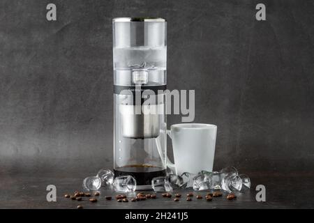 Moderne Cold Brew Drip Tower Kaffeemaschine auf dunklem Steinhintergrund Stockfoto