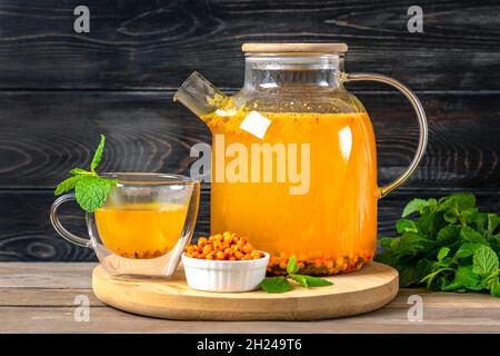 Teekannen und Tasse köstlichen und aromatischen Sanddorntee mit Minze und Honig auf Holztisch nützlich hat entzündungshemmende und Anti-Stress-Effekte Wi Stockfoto