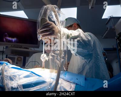 Selektiver Fokus auf die Hand des Chirurgen, die während der Operation ein Instrument in den Körper des Patienten einführt. Ärzte mit 3D-Brille führen laparoskopische Operationen mit modernen High-Tech-chirurgischen Geräten durch Stockfoto