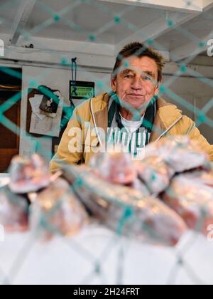 Ein Fischhändler und sein frisch gefangener Fisch wurden auf der Theke einer Frischfischhütte in Hastings Sussex England ausgestellt Stockfoto