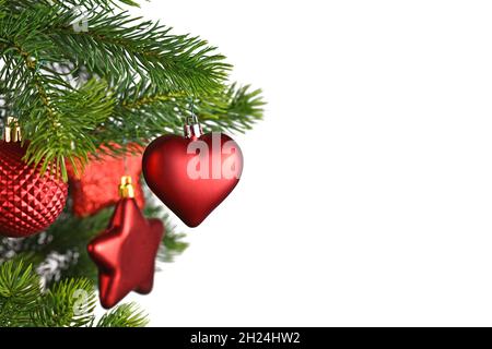 Rote herzförmige Weihnachtskugel auf geschmücktem Weihnachtsbaum auf weißem Hintergrund mit Kopierraum Stockfoto