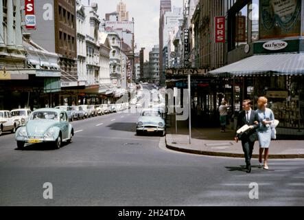 Ein Blick nach Westen auf die King Street, Sydney, NSW, Australien im Jahr 1964 von der Kreuzung mit der Castlereagh Street. Die normalerweise geschäftige Straße scheint sehr ruhig zu sein, so dass es durchaus ein Sonntag sein könnte. Die Gegend ist sehr verändert und alle Geschäfte rechts sind nun weg, ersetzt durch den Turm und den Einkaufskomplex des MLC Centers. Die King Street ist eine Straße im Stadtzentrum von Sydney. Dieses Bild stammt von einem alten Kodak-Amateurfotograf mit Farbtransparenz – einem alten Foto aus den 1960er Jahren. Stockfoto