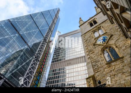 Alt und neu: Die St. Andrew Undershaft Church aus dem 15. Jahrhundert neben den Wolkenkratzern St. Helen's und Cheesegrater; City of London, England. Stockfoto