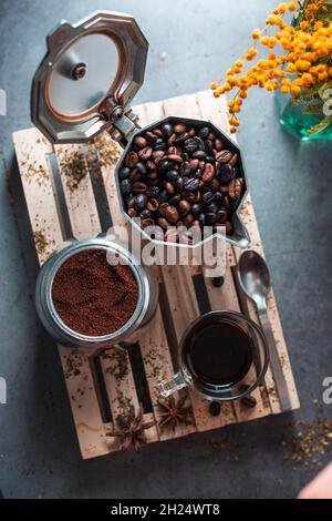 Kaffeebohnen und gemahlener Kaffee in der Kaffeekocher neben der Kaffeetasse. Stockfoto