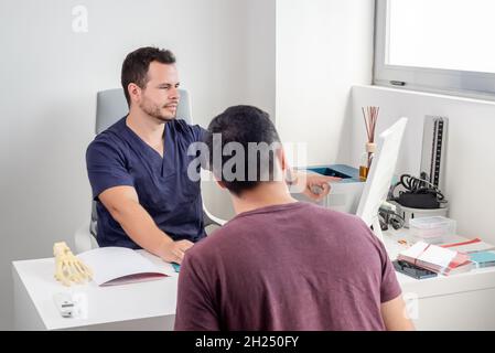 Physiotherapeut erklärt die Entwicklung eines Patienten auf einem Computerbildschirm. Stockfoto