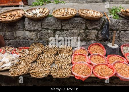 Körbe mit getrocknetem Fisch und Garnelen zum Verkauf auf der Straße in der alten Stadt Furong, China. Stockfoto