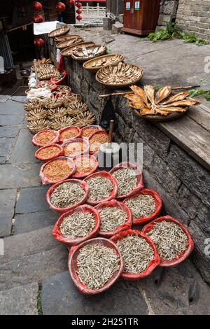 Körbe mit getrocknetem Fisch und Garnelen zum Verkauf auf der Straße in der alten Stadt Furong, China. Stockfoto