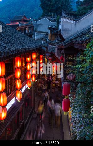 Eine lange Ausstellung von Menschen, die nachts in Fenghuang, China, eine enge Straße entlang gehen. Stockfoto