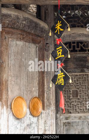 Gewebte Bambuskörbe und ein Banner mit chinesischen Schriftzeichen schmücken ein altes Gebäude in Furong, China. Stockfoto