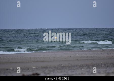 Verschiedene Schwerpunkte eines Strandes gegen das Meer mit einer kleinen schwimmenden Boje Stockfoto