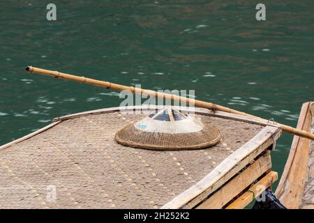 Ein überdachtes Ausflugsboot, das auf dem Fluss Tuojiang in Fenghuang, China, angedockt ist, mit einem traditionellen konischen Hut auf der Oberseite. Stockfoto