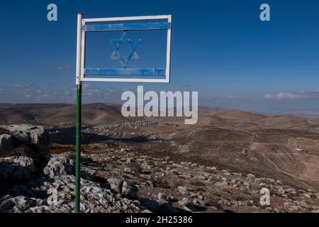 Die israelische Flagge aus Stahl, die am Matan Lookout über den Hügeln von Samaria, auch bekannt als Nablus-Berge, auf dem Gidonim-Bergrücken (ein Hügel, auf dem sich mehrere jüdische Siedlungen befinden), über der israelischen Siedlung Itamar am Westufer angebracht ist. Israel Stockfoto