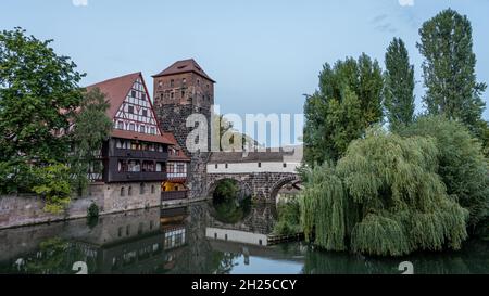 Schöne alte Brücke mit mittelalterlichem Turm und Fachwerkhaus entlang des Flusses mit Reflexionen in Nürnberg Stockfoto