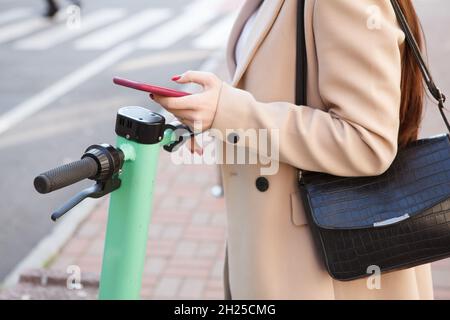 Unkenntlich Frau, die Elektroroller über mobile App mietet Stockfoto