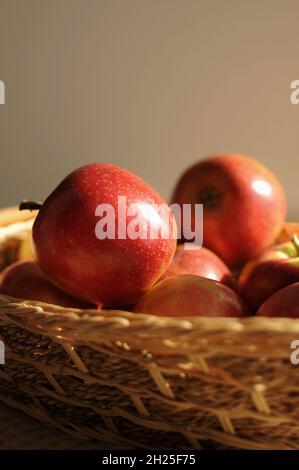 Nahaufnahme von roten Reifen Äpfeln im Strohkorb auf hellem Hintergrund. Ernte zu Hause Stockfoto