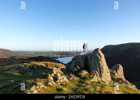 Walker genießt den Blick vom Gipfel des Steel Knotts (Pikeawassa) in Richtung Ullswater, Lake District, Cumbria, Großbritannien Stockfoto