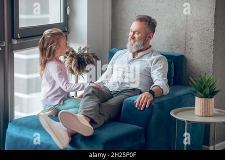 Ein reifer Mann, der mit seiner Tochter am Fenster sitzt Stockfoto