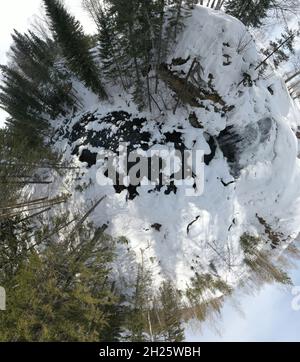 Kleiner Planet kleiner Planet Panorama-Luftaufnahme Wasserfall auf kleinen Bergfluss im Winterwald mit schneebedeckten Bäumen Stockfoto