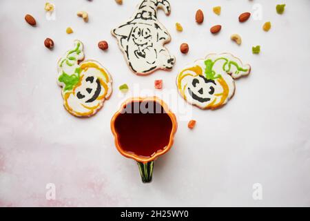 Halloween Kreativkonzept: Kürbisbecher und hausgemachte Kekse in Form von niedlichen Kürbissen und GeisterNahaufnahme. Ästhetische Herbststimmung oder Trick or Treat Konz Stockfoto