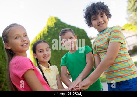 Glückliche Kinder halten die Hände als Zeichen einer starken Freundschaft Stockfoto