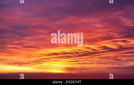 Seltene dramatische Dämmerung, Feuer, Sonnenaufgangshimmel in gelben, orangen und magentafarbenen Farben. Stockfoto