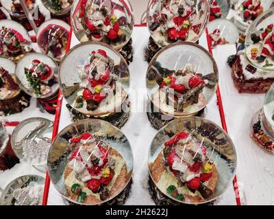 Weihnachtskugeln mit Schneekugel auf den Regalen des Spielwarenladens. Festliche Glaskuppeln mit Weihnachtsmann-Figuren schmücken, in der Shop-Galerie in Jumbo Stores in Thessaloniki, Griechenland ausgestellt. Stockfoto