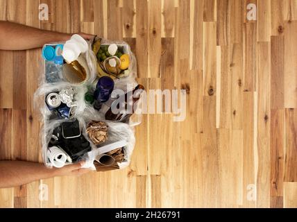 Mann, der getrennte Abfallstoffe auf einem grünen, isolierten Hintergrund hält. Abfallmanagement-Konzept Stockfoto