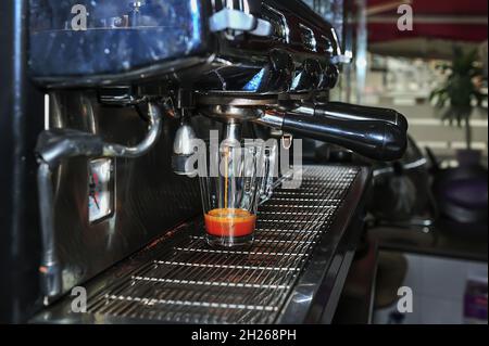 Der Kellner macht einen guten Kaffee in der Espressomaschine Stockfoto