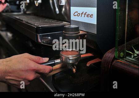 Der Kellner macht einen guten Kaffee in der Espressomaschine Stockfoto