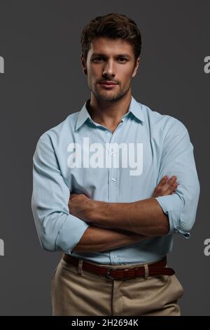 Porträt eines schönen selbstbewussten europäischen Geschäftsmannes mit gekreuzten Armen. Junger bärtiger Mann mit dunklem Haar trägt formelle Kleidung und schaut auf die Kamera. Ist Stockfoto