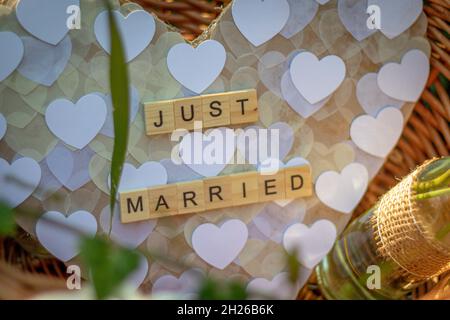 Ein Herz mit den gerade verheirateten Worten aus einzelnen Holzbuchstaben in einem Korb als Dekoration bei der Hochzeitsfeier Stockfoto
