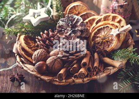 Getrocknete Orange, Sternanise, Zimt, Tannenzapfen und Tannenbaum in rustikalem Teller auf Holztisch. Hausgemachte Medley-Idee für Weihnachtsstimmung und Aroma. Öko-Frie Stockfoto