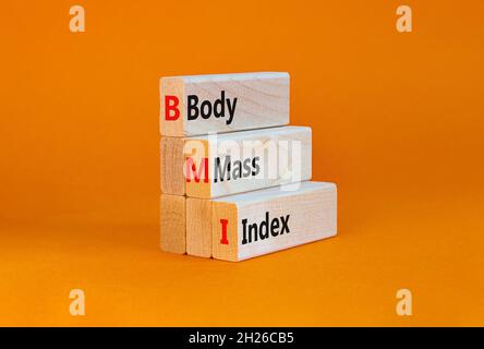 BMI-Body-Mass-Index-Symbol. Konzeptwörter „BMI Body Mass Index“ auf Holzblöcken auf einem schönen orangefarbenen Tisch mit orangefarbenem Hintergrund. Gesunder Lebensstil und Stockfoto