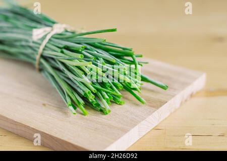 Ein Bund grüner Zwiebeln auf einem Holzbrett Stockfoto