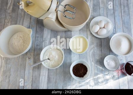 Der Prozess der Herstellung einer sauren Sahneschokolade Kuchen. Teigvorbereitung. Alle Zutaten für den Teig stehen auf dem Tisch bereit. Schritt für Schritt Rezept für Stockfoto