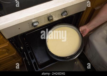 Ein Schritt-für-Schritt-Prozess für die Herstellung einer sauren Sahneschokolade Kuchen. Weibliche Hände legen fertigen rohen Teig in eine vorbereitete Auflaufform in einen heißen Ofen. Baki Stockfoto