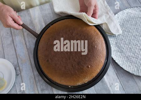 Schritt-für-Schritt-Prozess der Herstellung einer sauren Creme Schokolade Kuchen. Frauenhände nehmen den fertigen Kuchen aus dem Ofen und legen ihn auf eine Schüssel. Backconcep Stockfoto