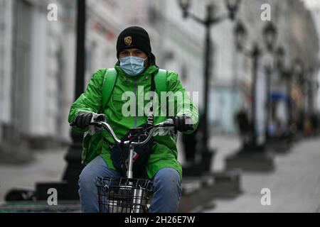 Moskau, Russland. Oktober 2021. Ein Mann mit Gesichtsmaske fährt am 20. Oktober 2021 in Moskau, Russland, mit dem Fahrrad. Russland bestätigte in den letzten 24 Stunden 34,073 neue COVID-19-Fälle, was die landesweite Summe auf 8,094,825 annahm, teilte das offizielle Überwachungs- und Reaktionszentrum am Mittwoch mit. Unterdessen stieg die Zahl der landesweiten Todesopfer um einen Rekordanstieg von 1,028 auf 226,353 pro Tag, und die Zahl der Genesungen stieg um 25,231 auf 7,065,712. Quelle: Evgeny Sinitsyn/Xinhua/Alamy Live News Stockfoto