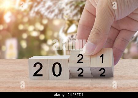 Neues Jahr 2020 Wechsel zu 2021. Drehen Sie die Hand über den Holzwürfelblock. Das Konzept der Neujahr-Ferien Stockfoto