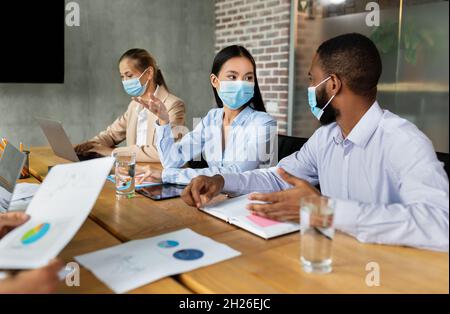 Diverse Geschäftsleute In Schützender Gesichtsmaske Nehmen An Der Konferenz Im Büro Teil Stockfoto