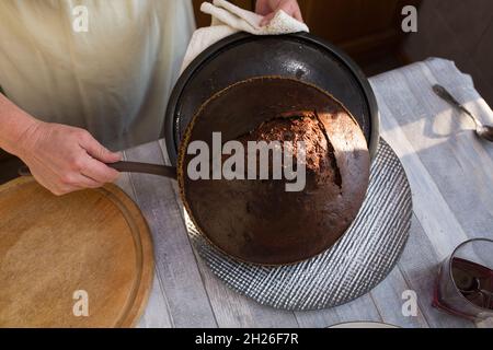 Schritt-für-Schritt-Prozess der Herstellung einer sauren Creme Schokolade Kuchen. Frauenhände nehmen den fertigen Kuchen aus dem Ofen und legen ihn auf eine Schüssel. Backconcep Stockfoto