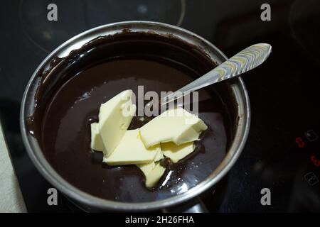 Schritt-für-Schritt-Verfahren für die Herstellung einer sauren Sahneschokolade Kuchen. Der Prozess der Herstellung von Schokolade Glasur. Der erhitzten Mischung aus saurem Crea wird Butter hinzugefügt Stockfoto