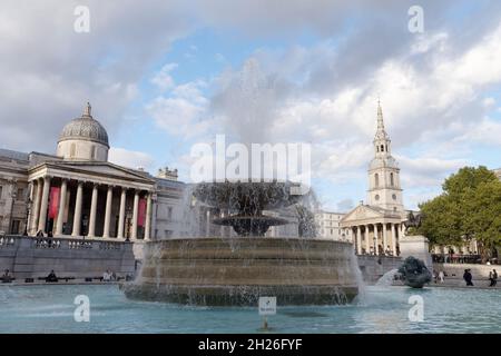 London, Greater London, England, Oktober 05 2021: Wasser fließt aus einem Brunnen am Trafalgar Square, während Touristen an der National Gallery in der BA vorbeilaufen Stockfoto